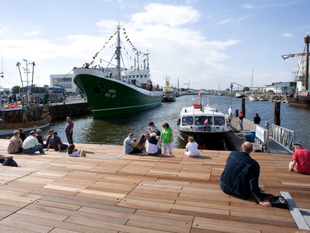 Auf den Stufen im Schaufenster Fischereihafen sitzen und Fischbrötchen genießen