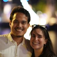 Ein Pärchen vor einem Segelschiff lächelt in die Kamera