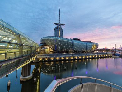 Klimahaus mit beleuchteter Glasbrücke im Abendlicht