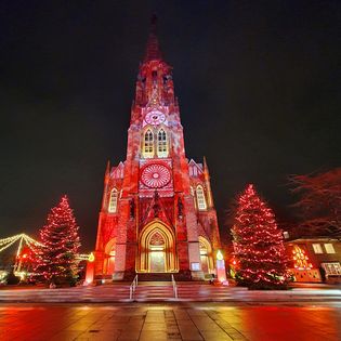 Beleuchtete Große Kirche mit Weihnachtsbäumen daneben