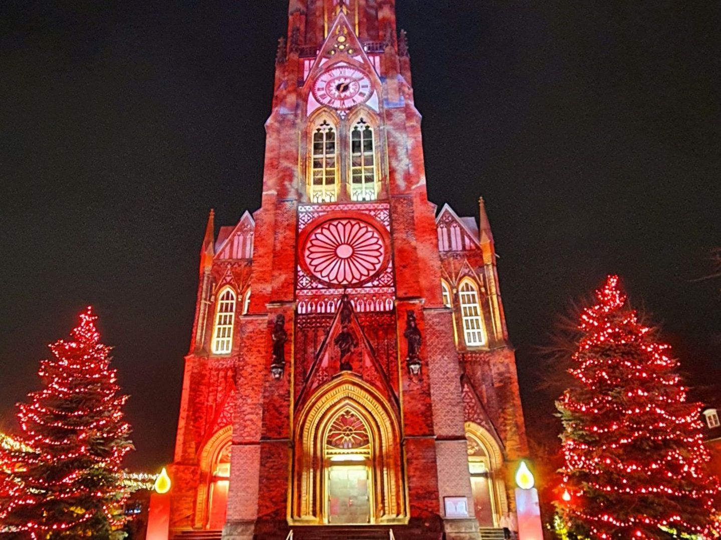 Beleuchtete Große Kirche mit Weihnachtsbäumen daneben