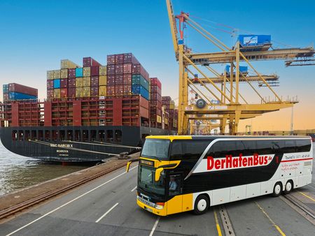 Ein Bus steht auf der Containerkaje im Hafen vor einem großen Containerschiff