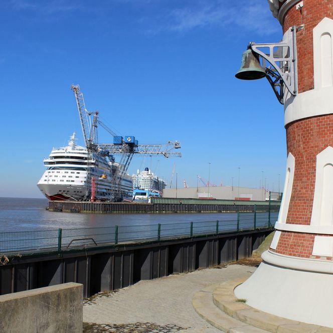 Der Pingelturm im Vordergrund, ein Kreuzfahrtschiff im Hintergrund mit blauem Himmel