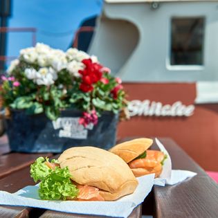 Zwei Fischbrötchen und Blumenarrangement auf dem Tisch an Bord eines Kutters