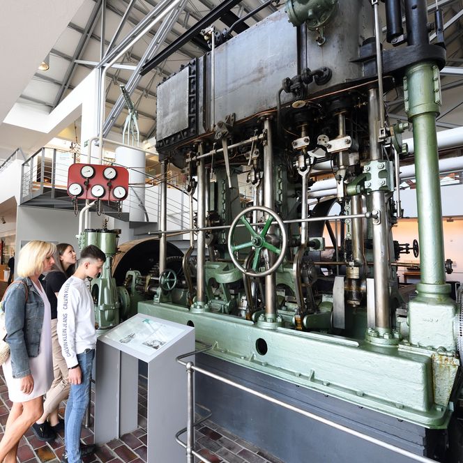 Besucher betrachten eine große historische Dampfmaschine im Industriemuseum Bremerhaven.