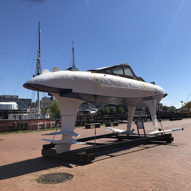 Tragflügelboot WSS10 aufgeständert im Museumshafen Bremerhaven vor blauem Himmel und Schiffsmasten.