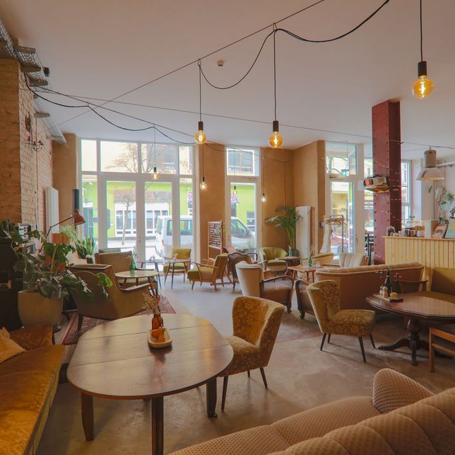 Heller Gastraum des Cafés Findus mit verschiedenen Vintage-Sitzmöbeln und Backsteinwand.