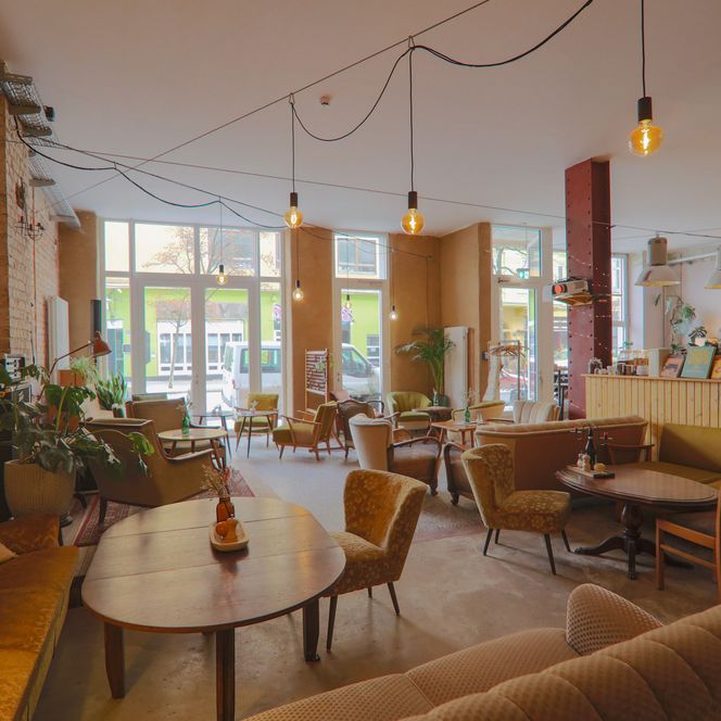 Heller Gastraum des Cafés Findus mit verschiedenen Vintage-Sitzmöbeln und Backsteinwand.