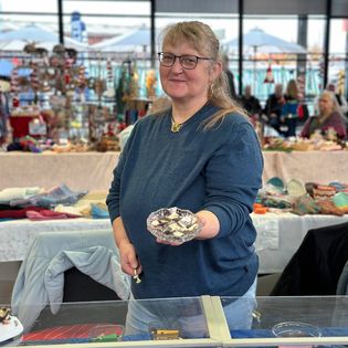 Eine Verkäuferin präsentiert ihre Ware auf dem Bauernmarkt im Schaufenster Fischereihafen