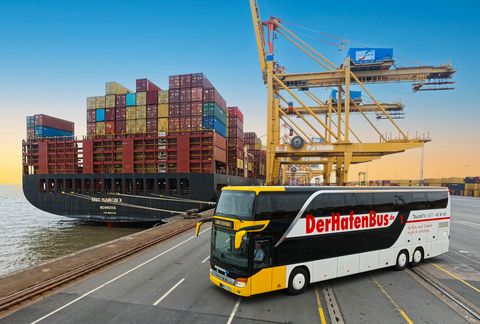 Ein Bus steht auf der Containerkaje im Hafen vor einem großen Containerschiff